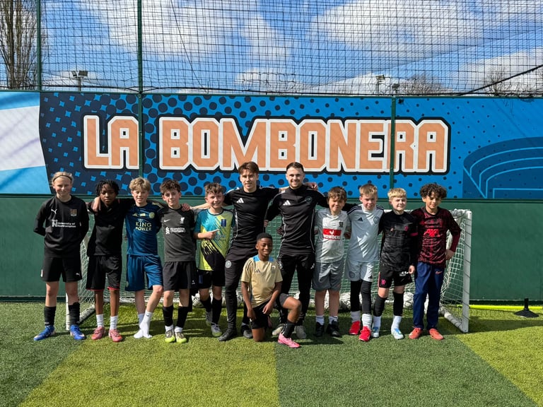 Youth soccer team posing in front of La Bombonera stadium sign on field