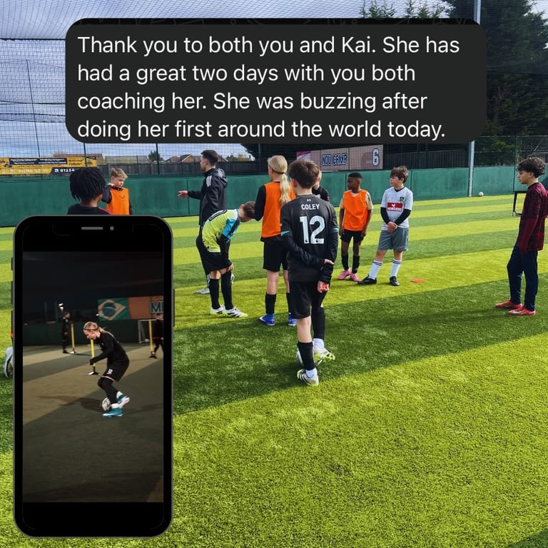Young soccer players in orange and black jerseys at a training session on a grass field with coaches. A smartphone displays a related soccer training moment.